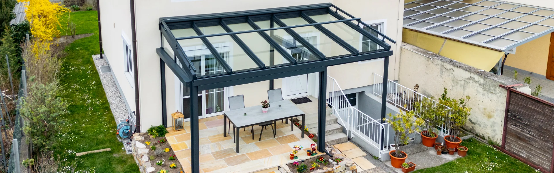 Terrassenüberdachung aus Aluminium mit transparentem Glasdach für Gartenbereich in Eisenstadt.