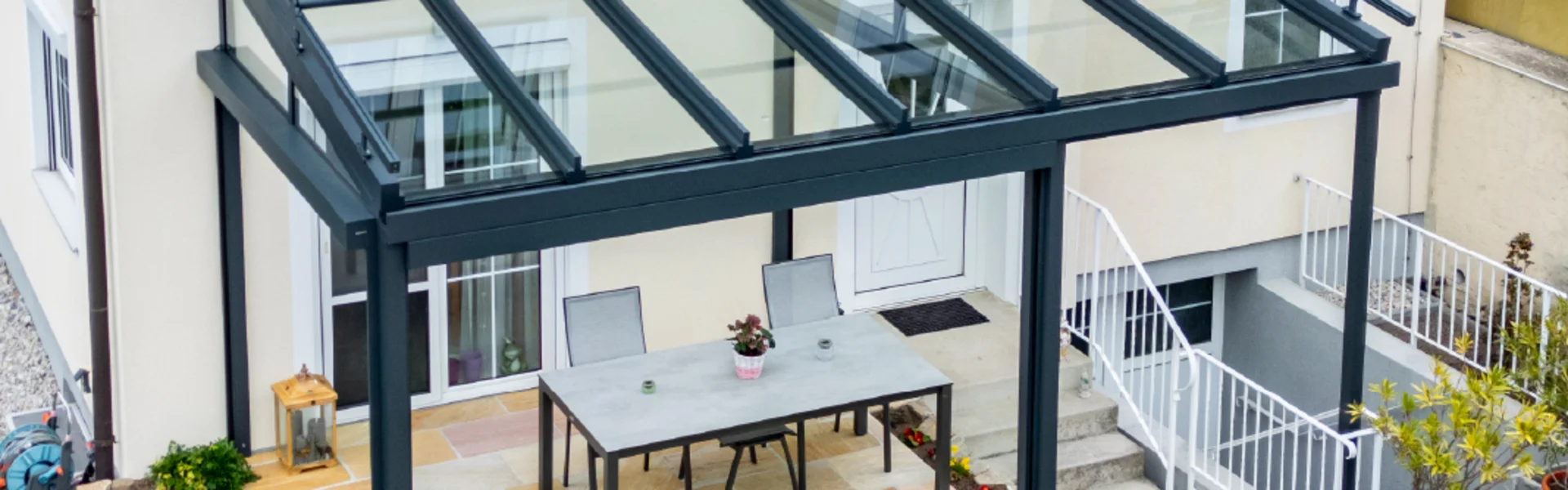Terrassenüberdachung aus Aluminium mit transparentem Glasdach für Gartenbereich in Eisenstadt.