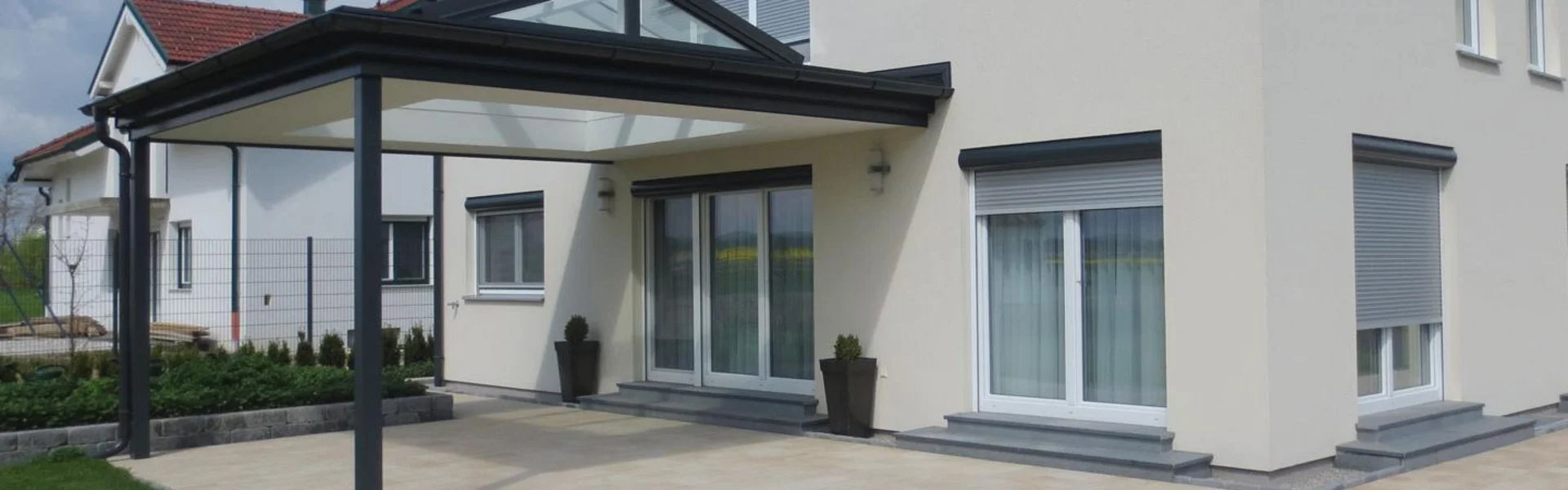 Einfamilienhaus mit beiger Fassade und Terrassenüberdachung in anthrazit für Korneuburg.
