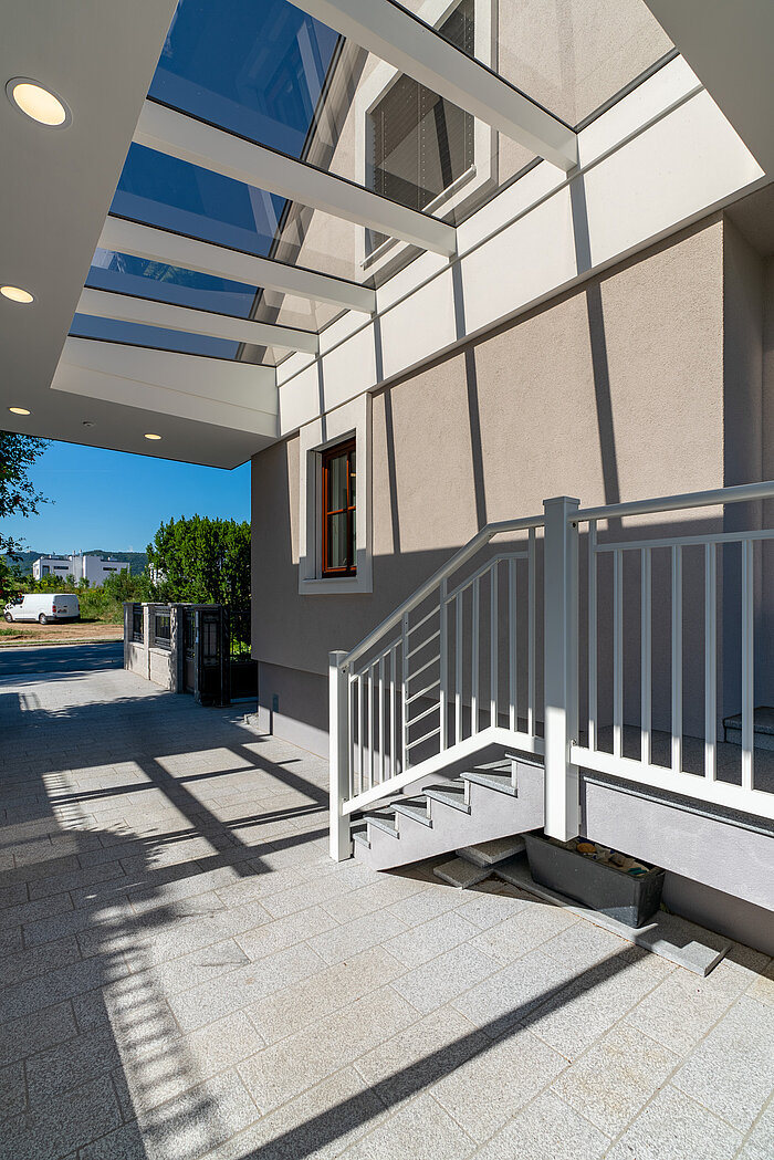 Carport im Eingangsbereich mit massivem Dach und Glasgiebel für mehr Licht in Wiener Neustadt.